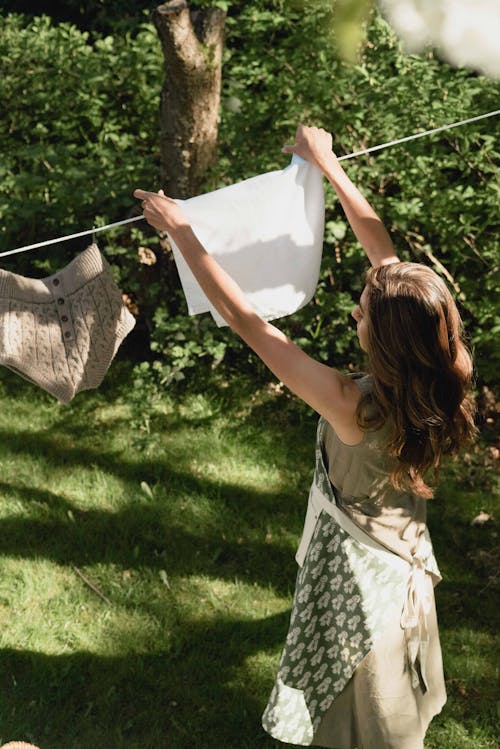 Free A Woman Hanging a White Cloth on a Clothes Line Stock Photo