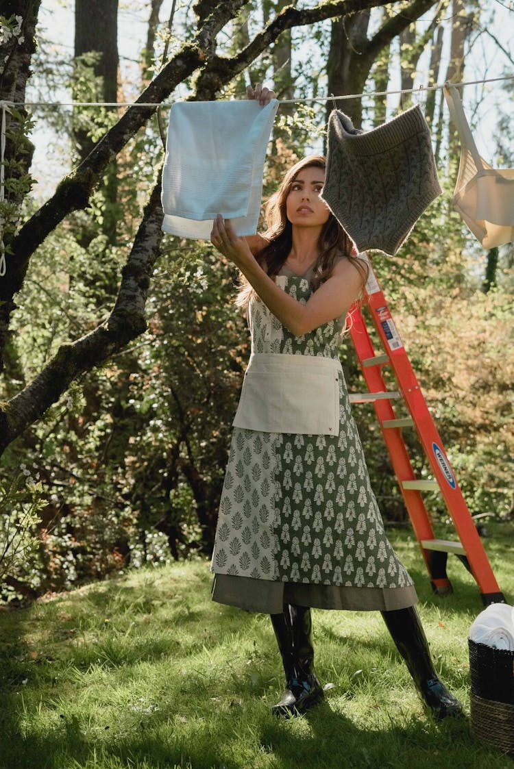 A Woman Hanging A White Towel On Clothes Line