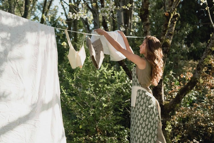 A Woman Putting A White Towel On Clothes Line