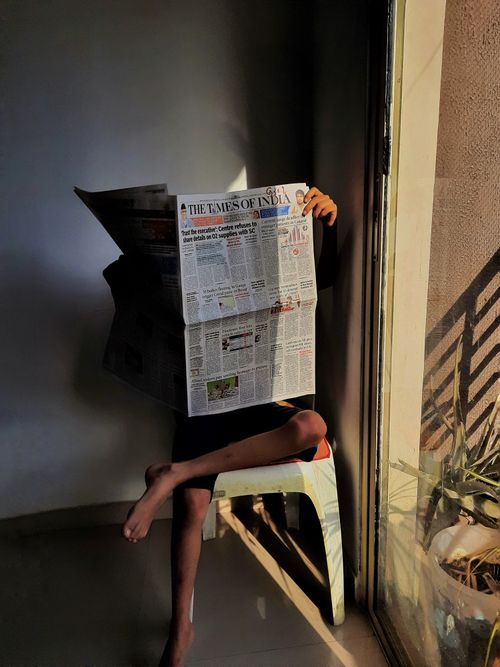 Free An individual enjoying a newspaper in a sunlit corner, highlighting leisure and relaxation. Stock Photo