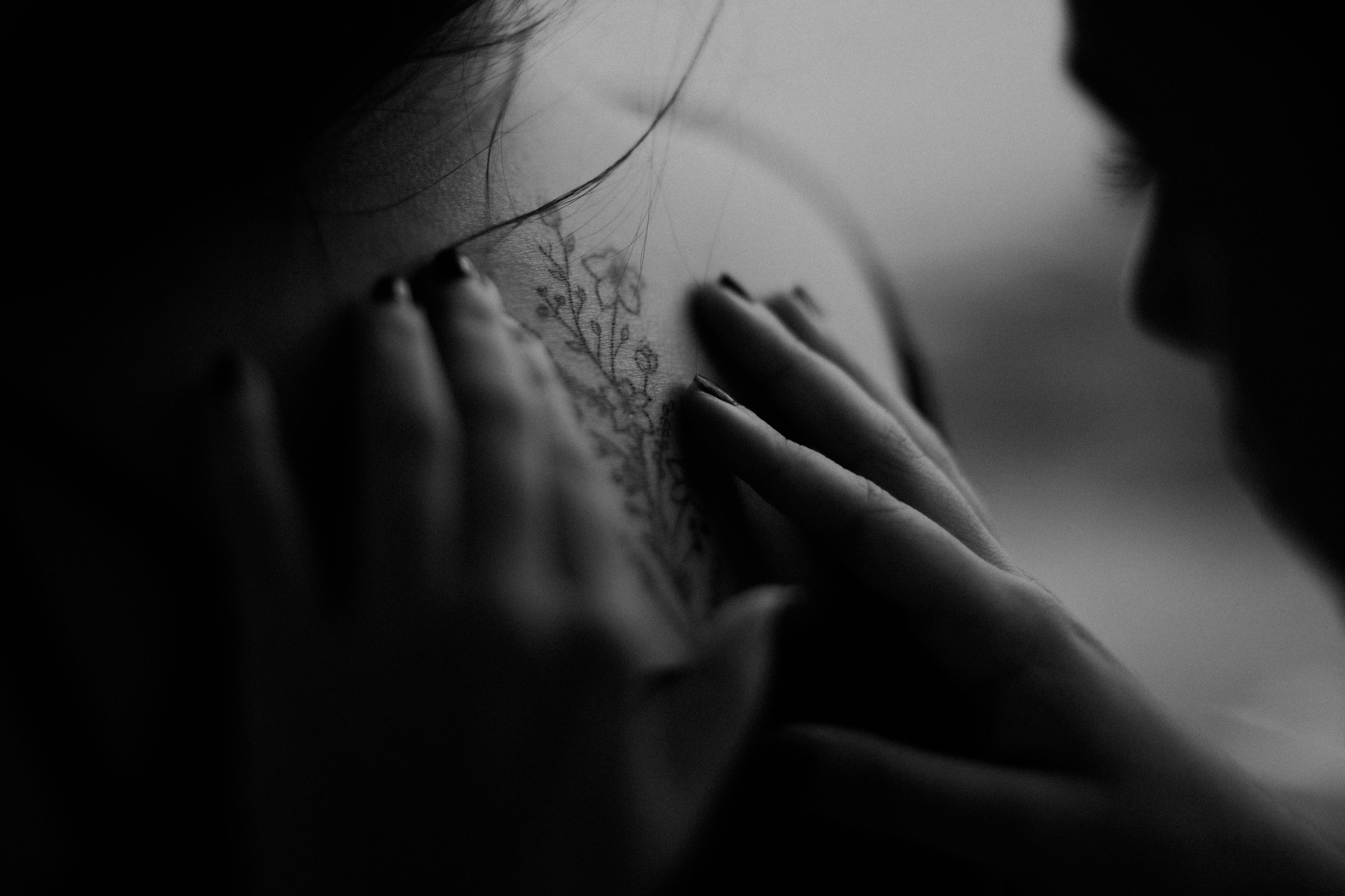 grayscale photo of man looking at woman s back flower tattoo