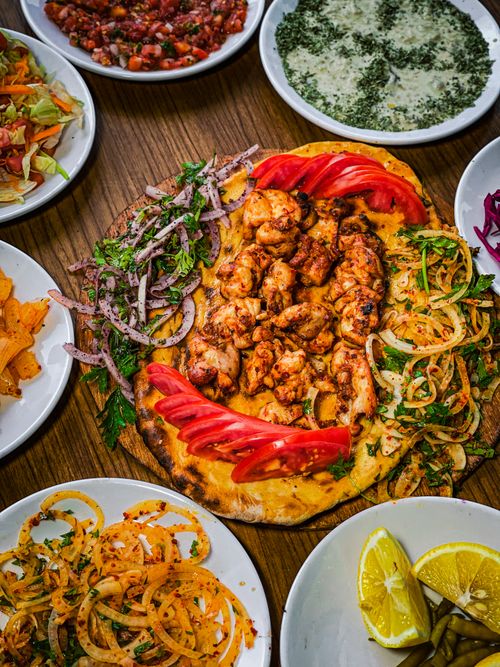 Free Flatlay of assorted Middle Eastern dishes featuring grilled chicken on pita, surrounded by vibrant sides. Stock Photo