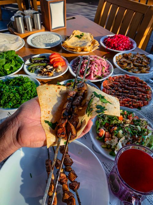 Free Delicious Middle Eastern meal with various fresh dishes and skewers on a wooden table. Stock Photo