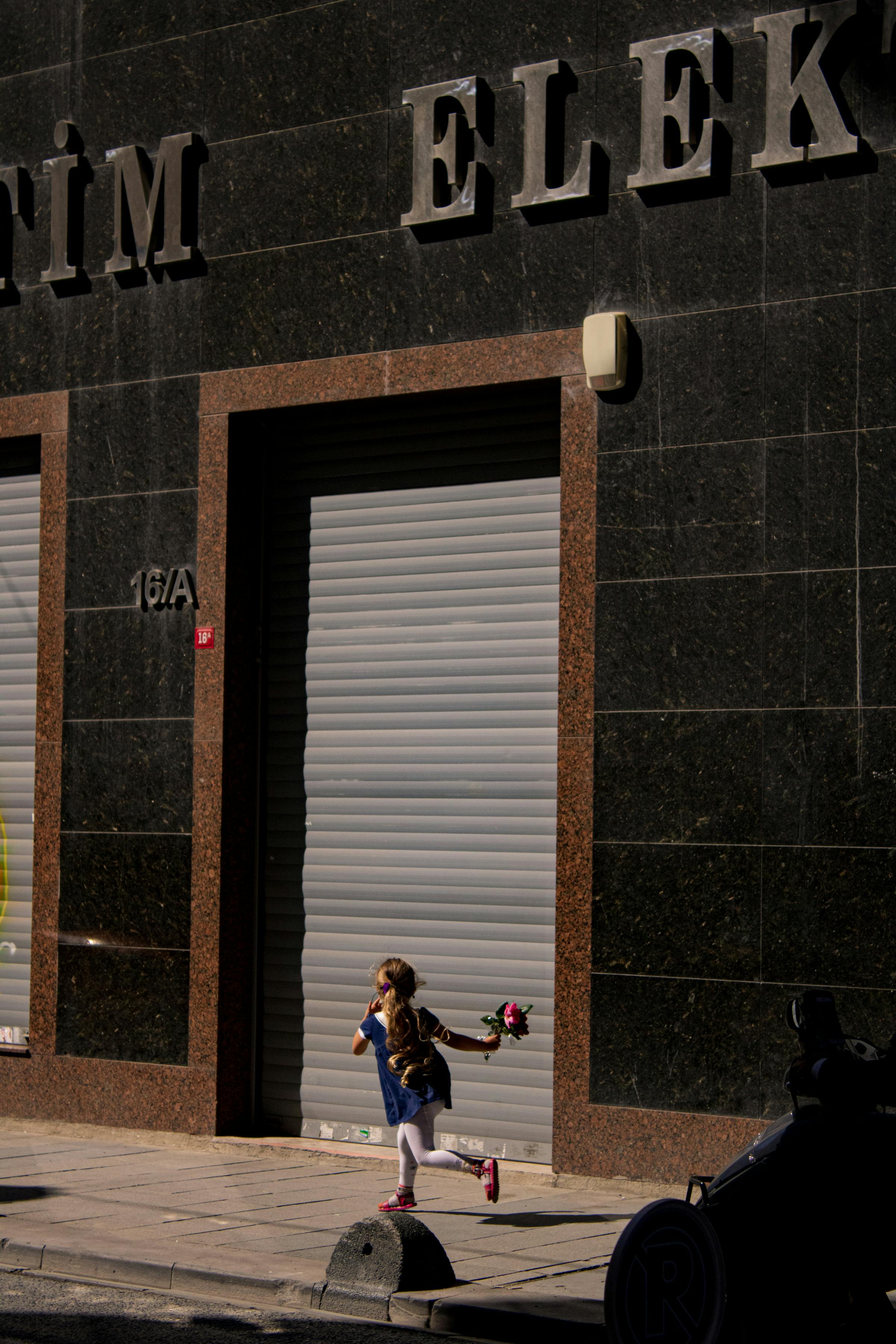 A young child runs along a sunlit sidewalk in Istanbul, Türkiye.