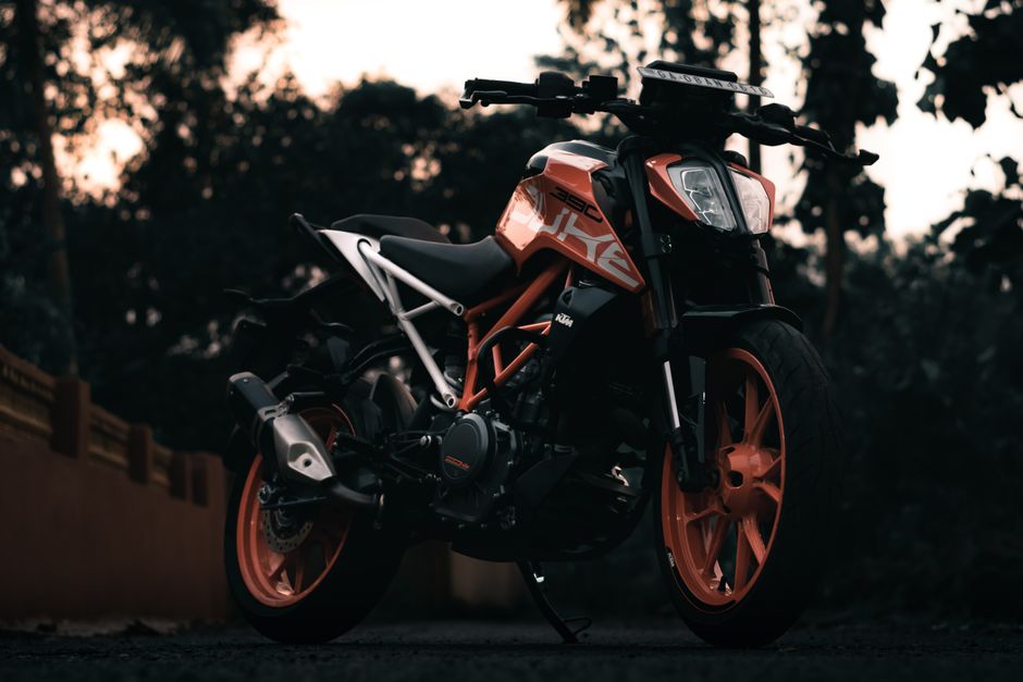A stylish orange motorcycle parked outdoors at dusk, showcasing its sleek design and vibrant style.
