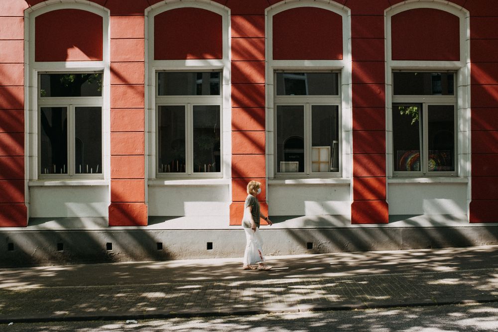 A woman walking down a quiet sunlit street — photo by Tasso Mitsarakis on Pexels
