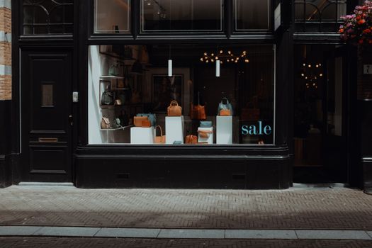 Stylish boutique storefront featuring elegant handbags on sale, inviting window display.