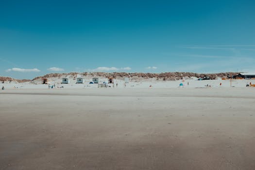 A tranquil beach scene with dunes and a clear blue sky, capturing the essence of summer relaxation.