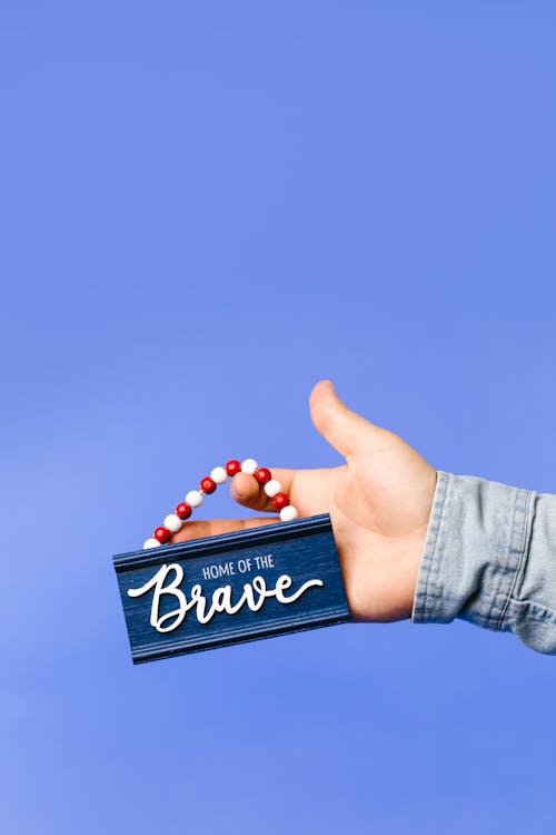 Hand Holding a Wooden Home Decoration with Beads and Embossed Word