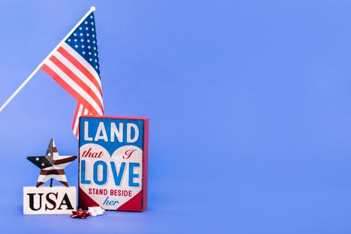 Free American flag with 'Land that I Love' sign against a blue background. Perfect for patriotic themes. Stock Photo