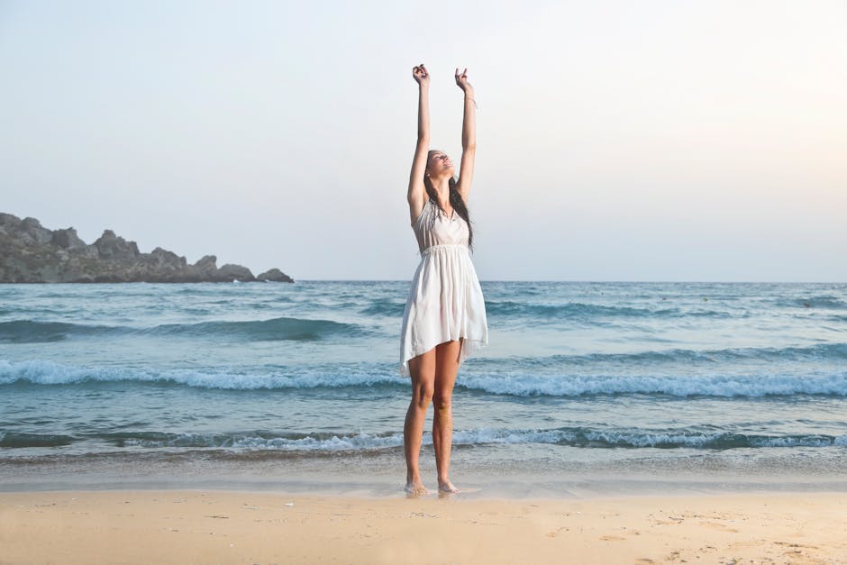 Photo of Woman in White Sleeveless Dress Raising Hands