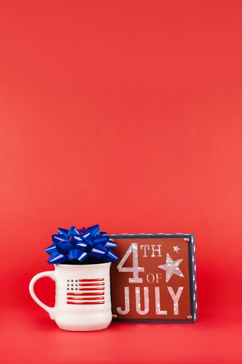 Free Decorative setup for Independence Day with a mug and 4th of July sign on a red background. Stock Photo