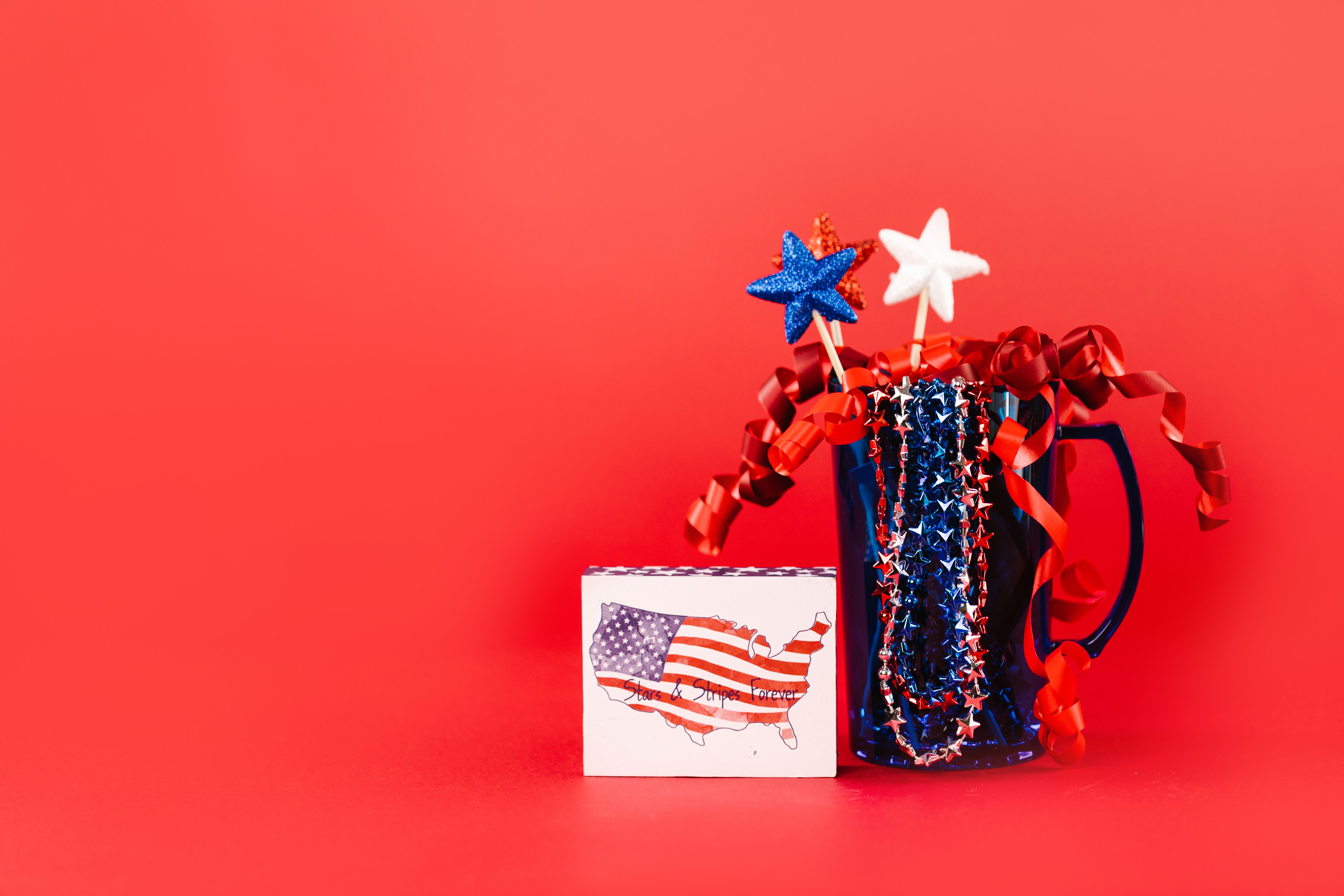A festive display of red, white, and blue patriotic decor against a vibrant red background, perfect for July 4th celebrations. — Foto: RDNE Stock project / Pexels