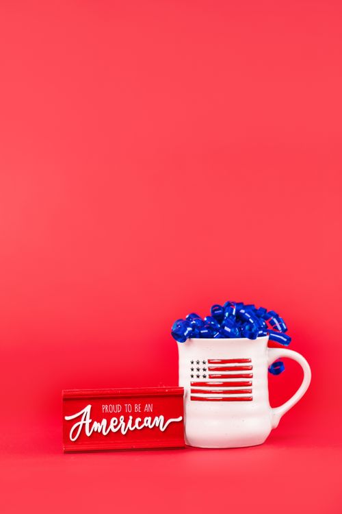 Free American flag mug with blue ribbons and a sign on a red background, perfect for Independence Day decor. Stock Photo