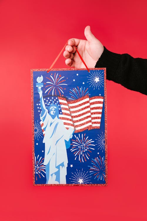 A Person Holding a Hanging Decoration with American Flag and Statue of Liberty Design