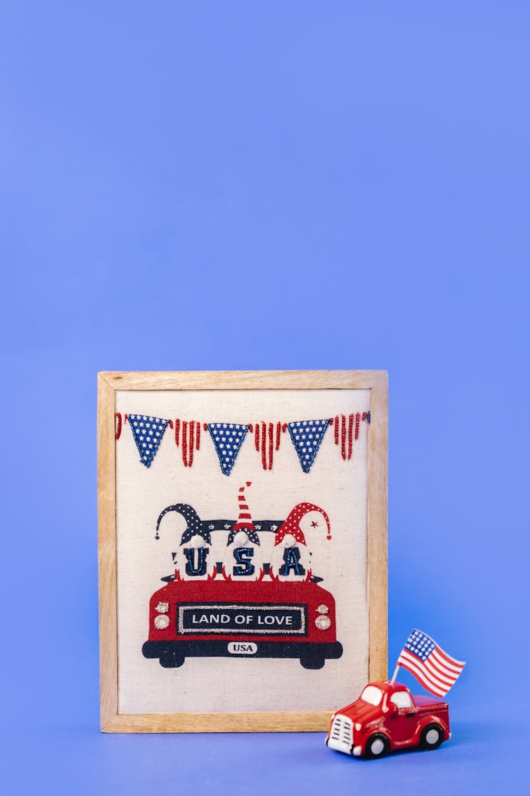 A Wooden Picture Frame Decoration Beside A Miniature Car With The American Flag