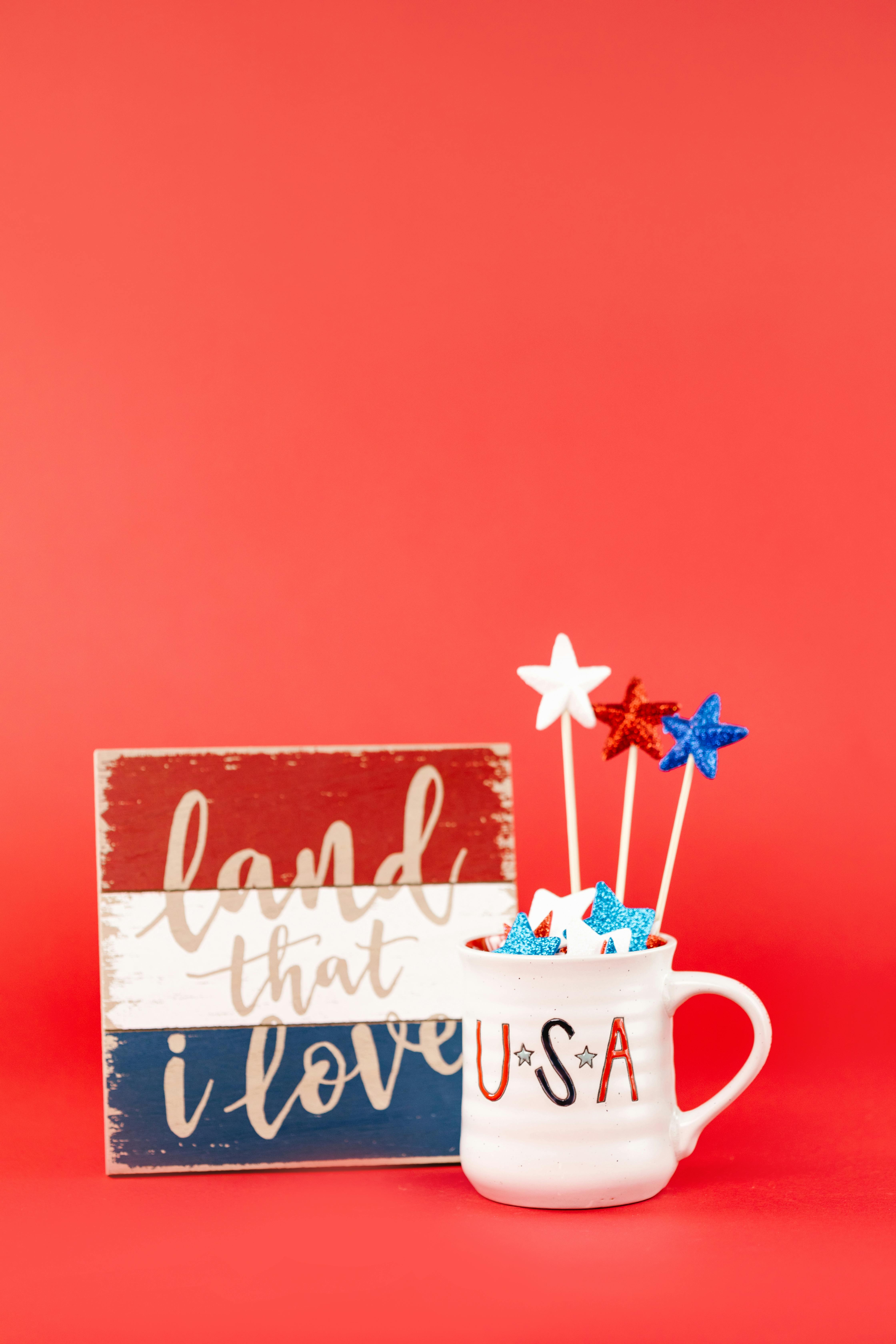 A festive USA-themed mug and wooden sign with red, white, and blue stars on a vibrant background.
