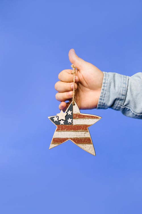 Person Holding a Star Shaped Hanging Ornament With Stars and Stripes