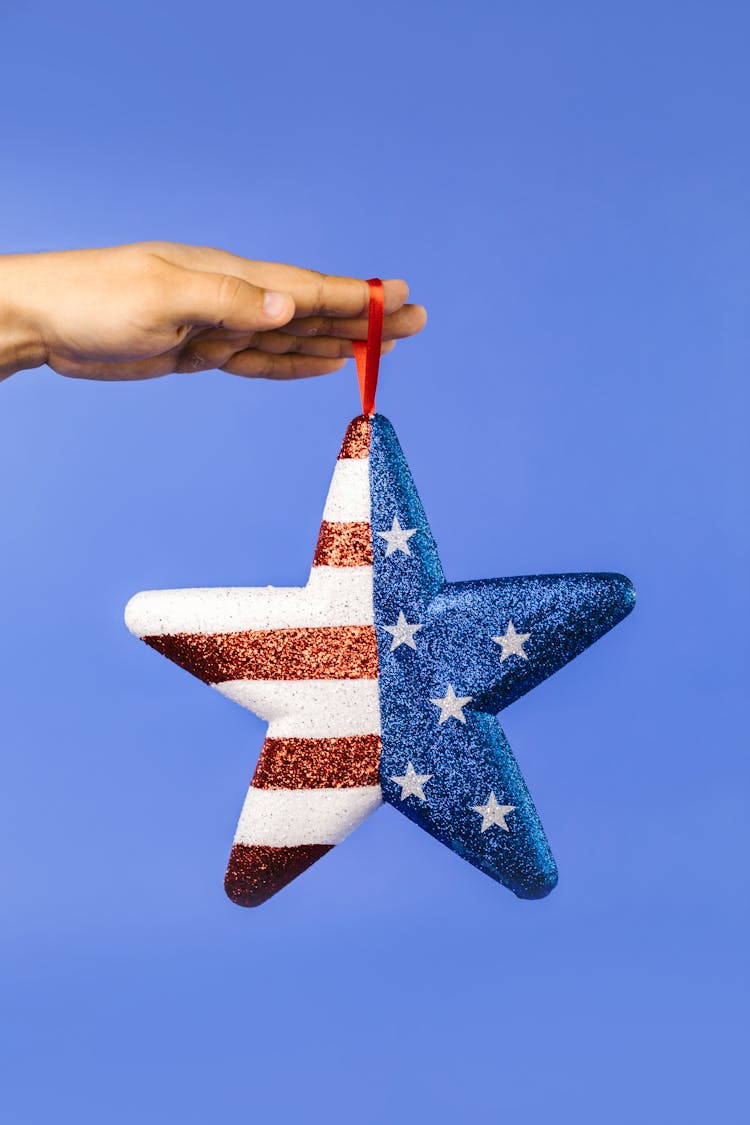 A Star With Stars And Stripes Hanging On A Person's Hand