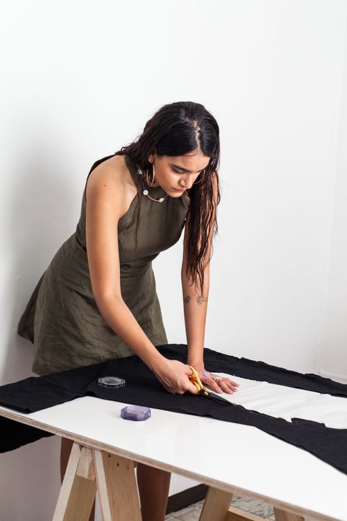 Free Young woman sewing and cutting fabric in a fashion design studio. Stock Photo