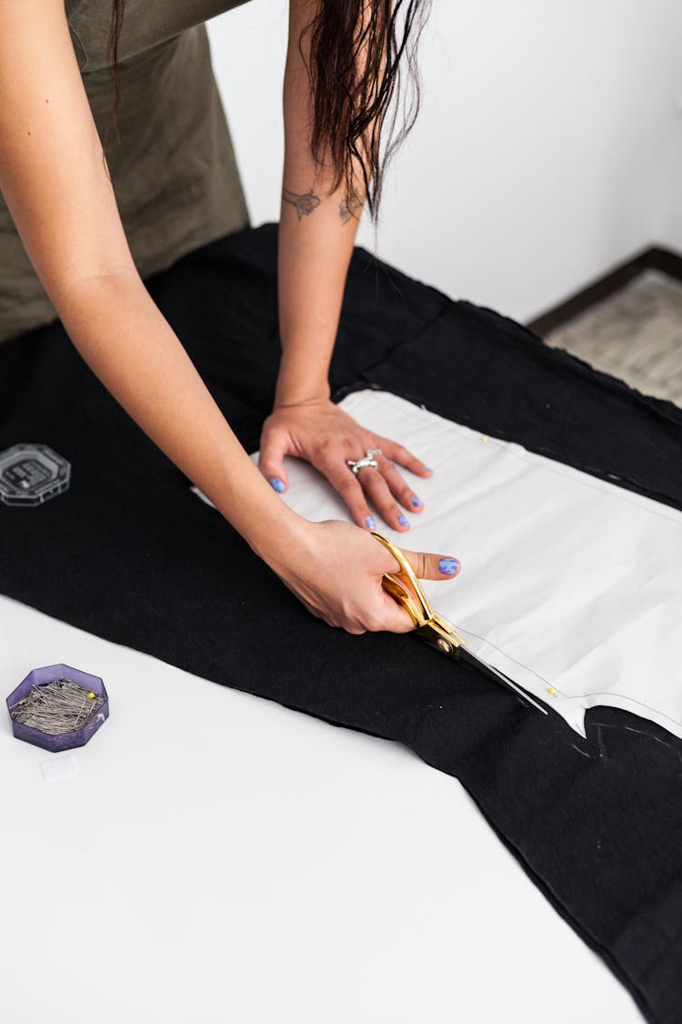 A Person Cutting A Fabric