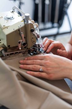 Detailed close-up of hands sewing fabric using a professional machine.