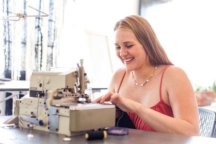 A Smiling Woman Using A Sewing Machine