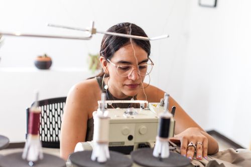Free Young woman using sewing machine in a design studio, focused and creative. Stock Photo