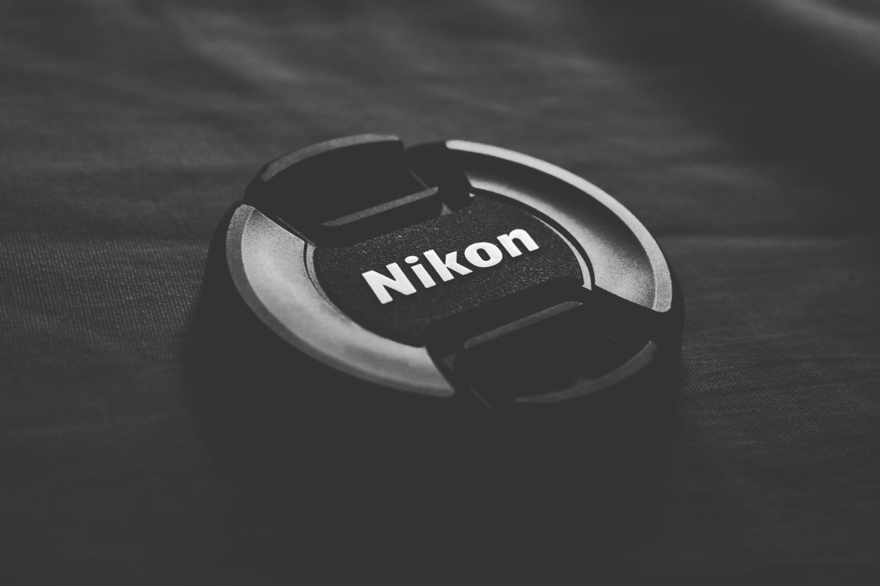 black nikon lens cap on dark textured surface minimalist and sleek des