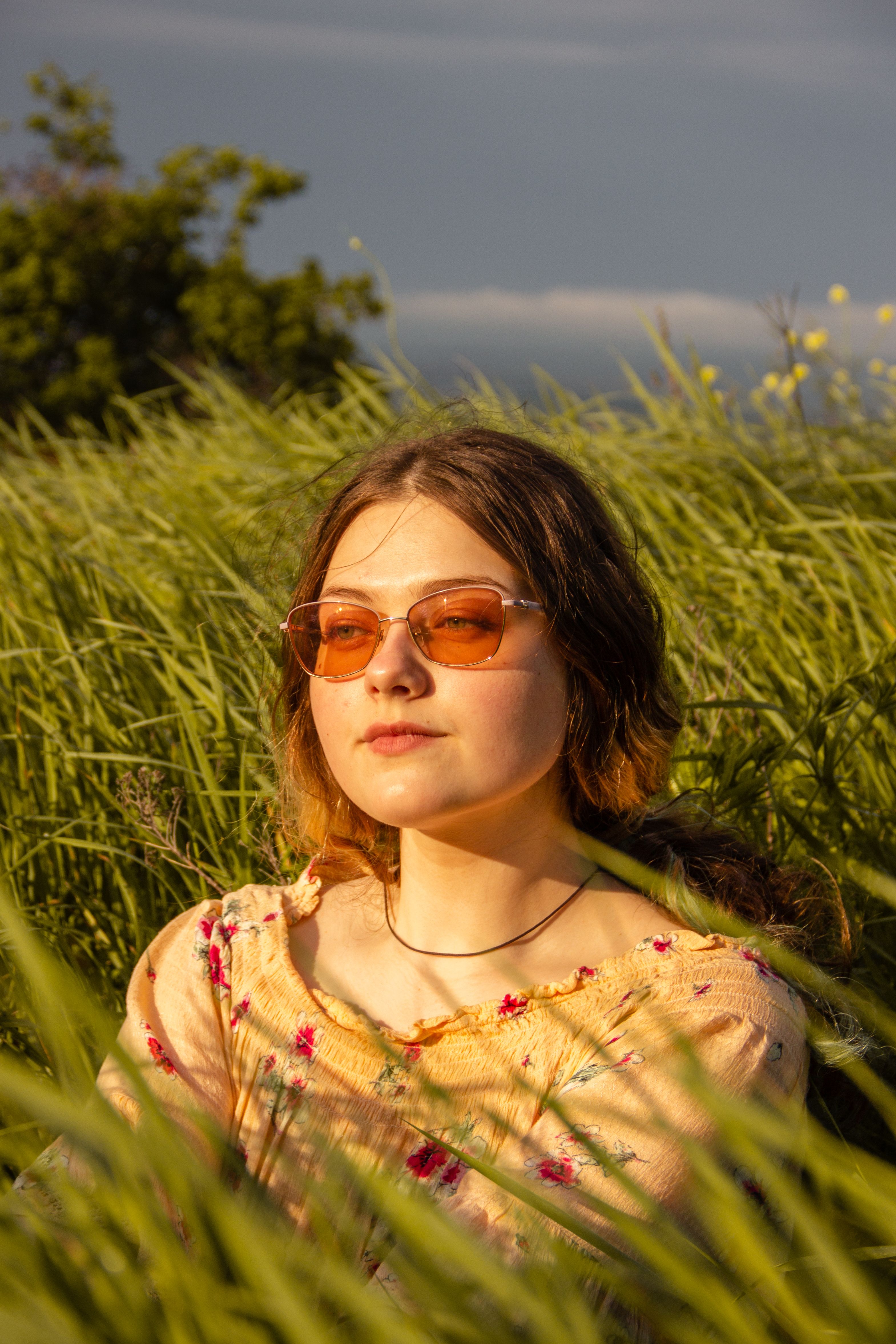 A serene portrait of a woman in sunglasses enjoying nature in a lush meadow.