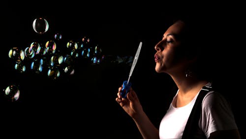 Woman in White Tank Top Playing With Soap Bubbles