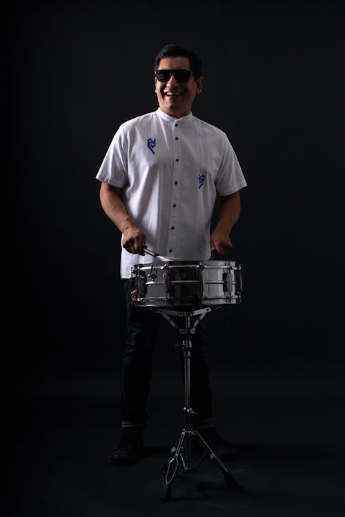 Man in White Polo Using a Drum 