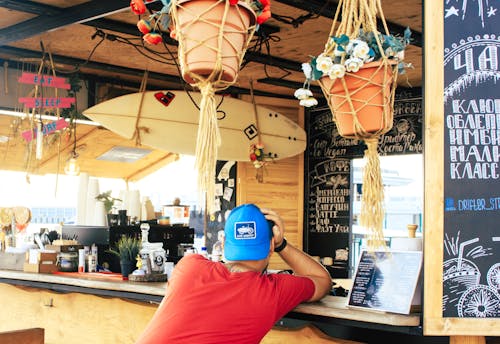 Man Near Counter Desk With Hanging Surfboard