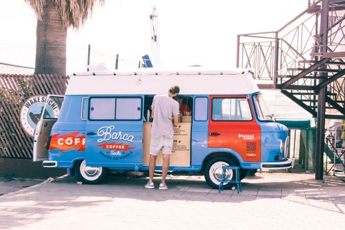 Free A vibrant coffee van serving drinks outdoors on a sunny day, attracting people. Stock Photo