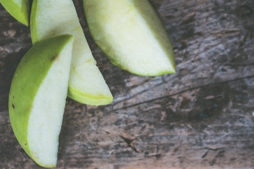 Close-Up Photography of Sliced Green Fruit on Brown Wooden Surface