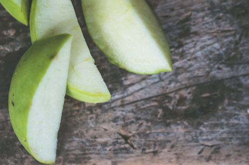 Free Close-up view of fresh green apple slices on a rustic wooden surface. Stock Photo
