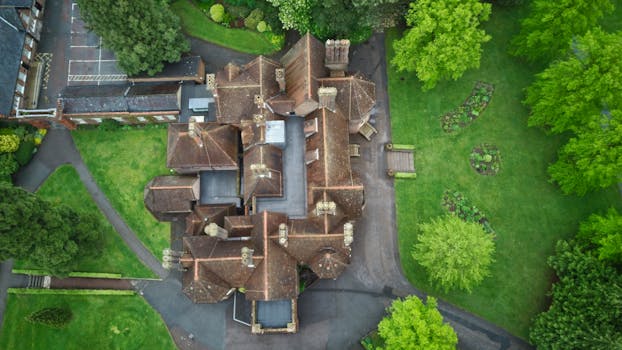 Top-down drone view of a historic mansion surrounded by lush greenery in Luton, UK.