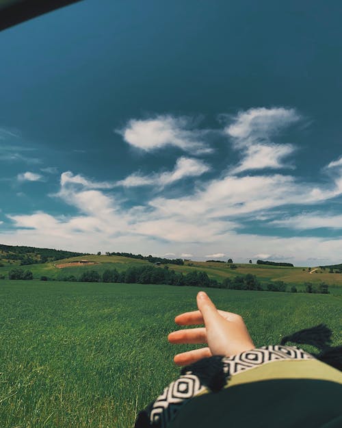 Unrecognizable person on grassy field under blue sky