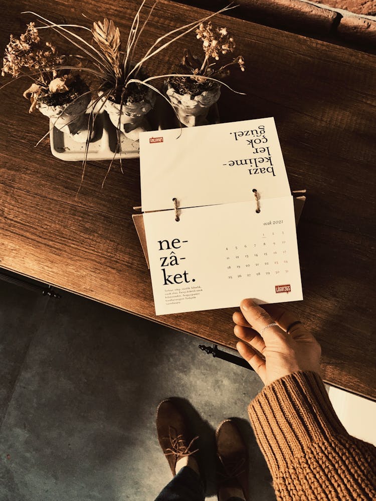 A Person Holding A Page Of A Table Calendar