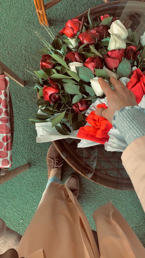 Free Top-down view of a person arranging red and white roses on a table indoors. Stock Photo