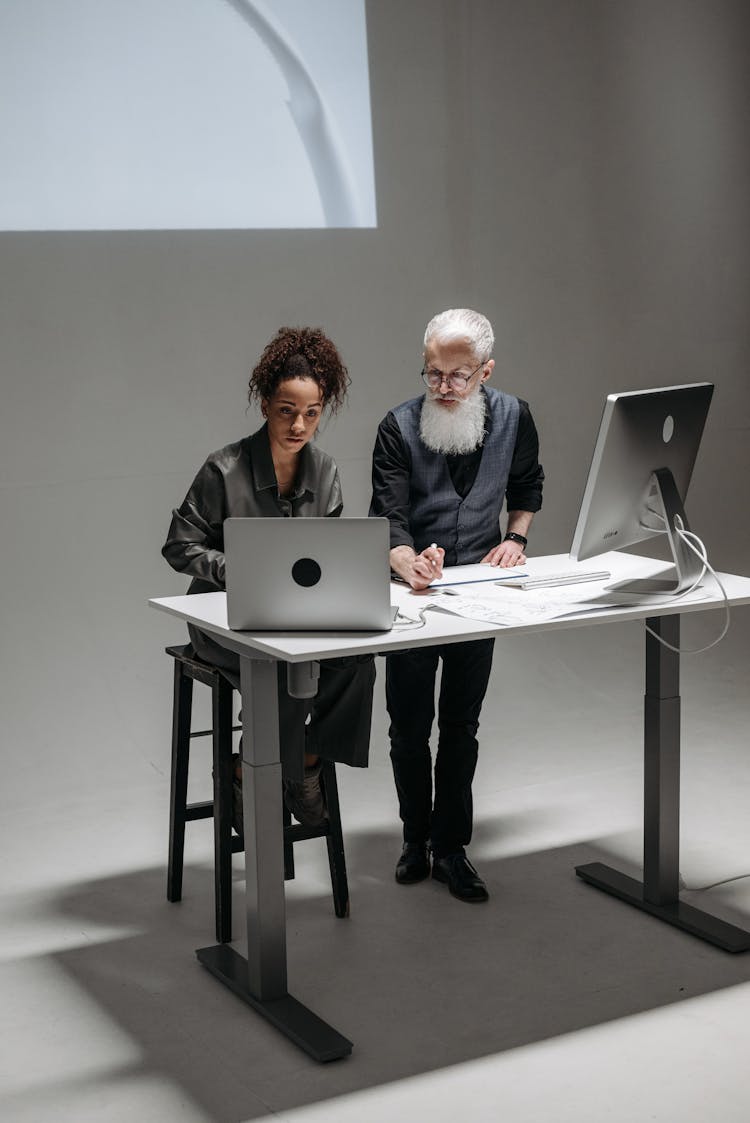 Two People Standing At A Desk