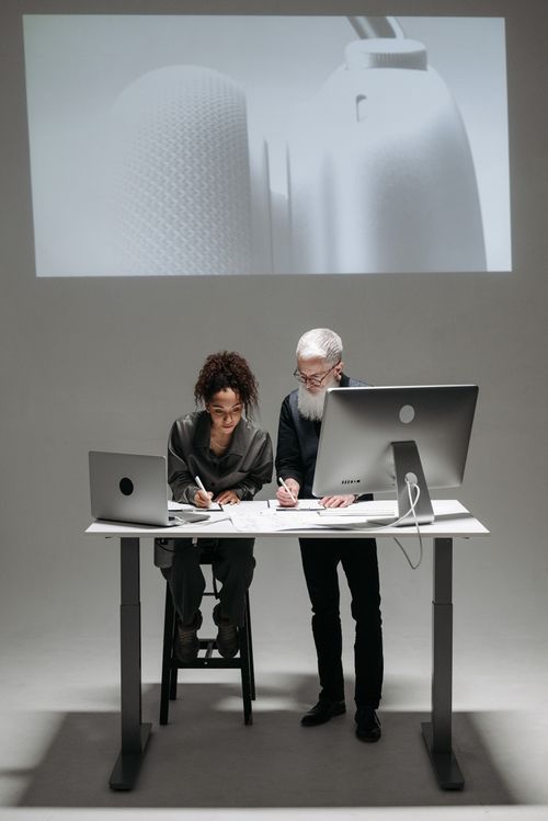 Free Two professionals collaborate in a high-tech setting with laptops and digital screens. Stock Photo