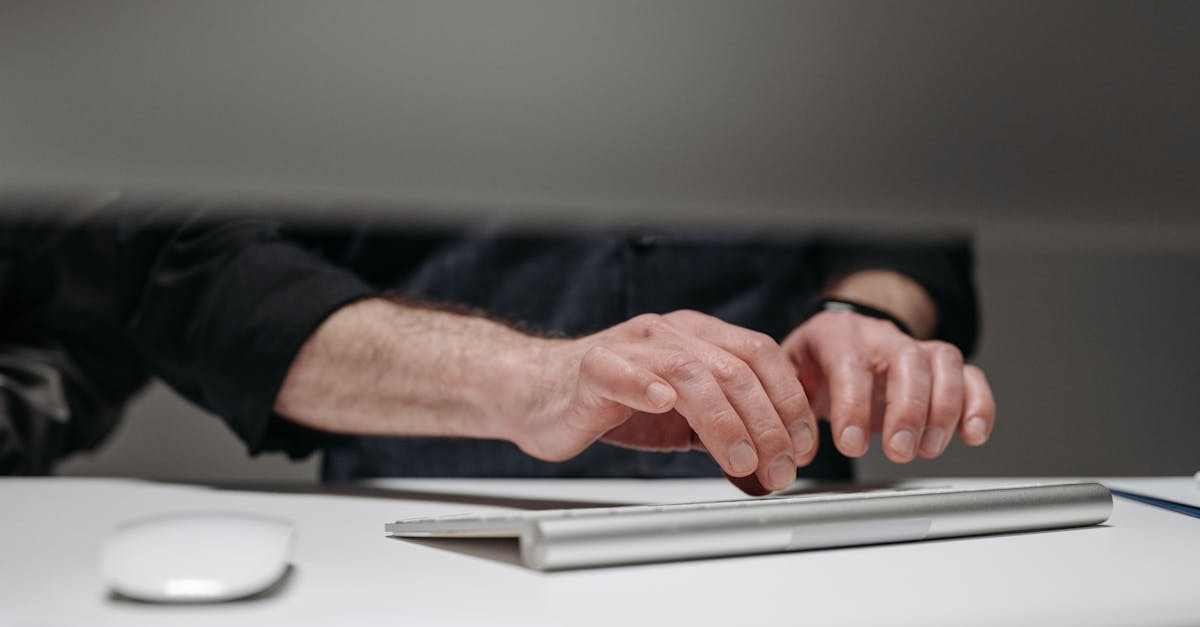 Detailed focus on adult male hands typing on a sleek keyboard, ideal for tech and business contexts.