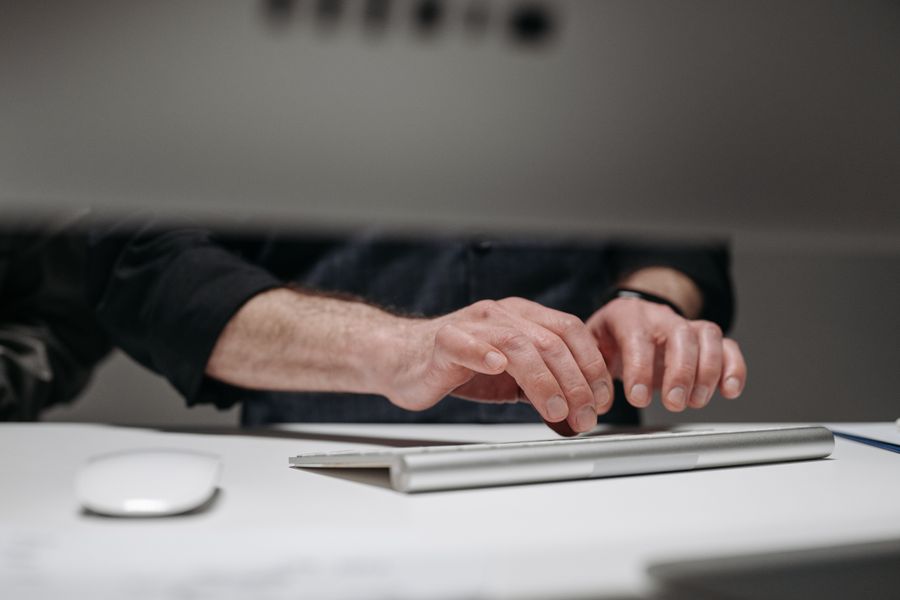 Detailed focus on adult male hands typing on a sleek keyboard, ideal for tech and business contexts.