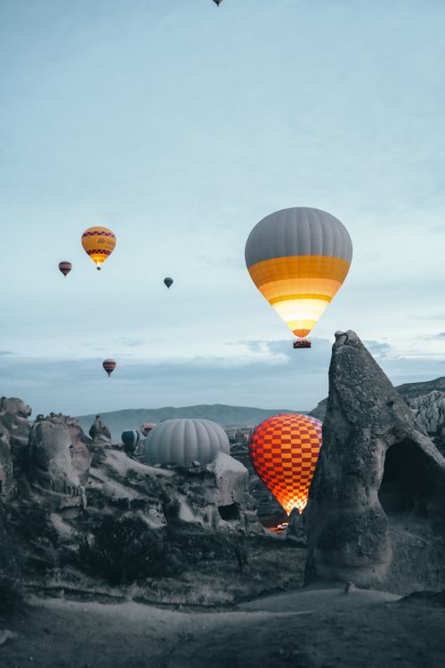 Free Colorful hot air balloons float above the unique rock formations of Cappadocia at sunrise. Stock Photo