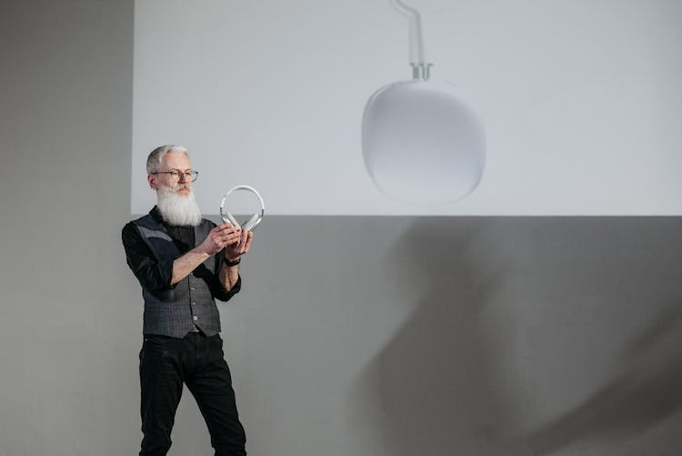 A Bearded Businessman Holding Wireless Headphones At A Presentation