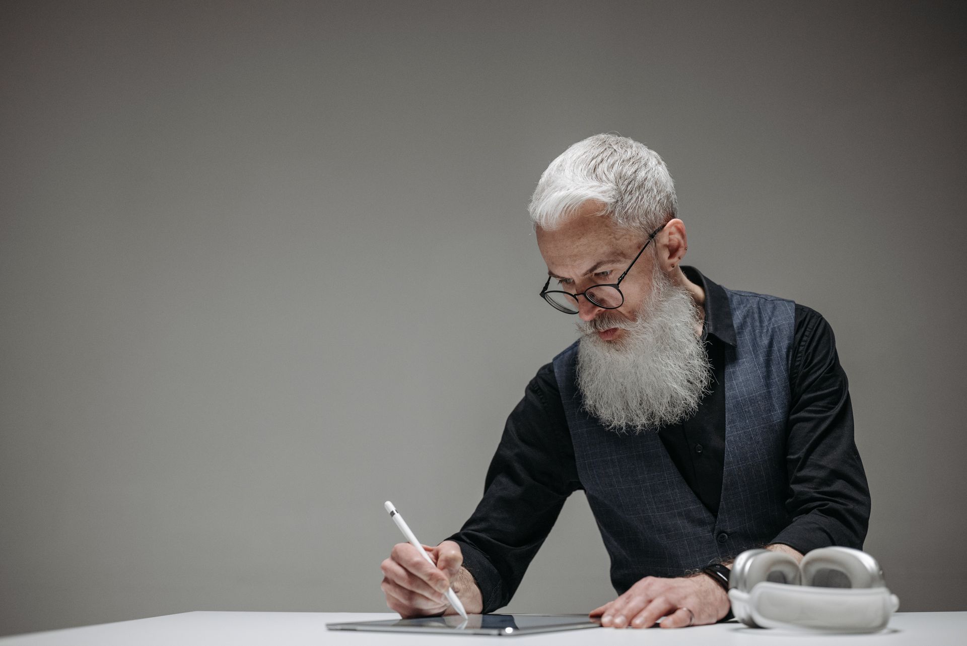 Elderly businessman using a tablet and stylus for technology work in a studio.