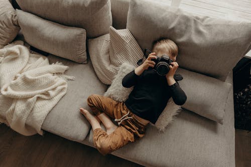 A Boy Reclining on a Couch While Using a Camera