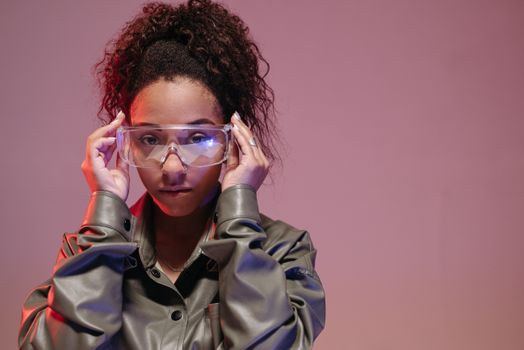 Woman wearing protective goggles in a studio setting with dramatic lighting.