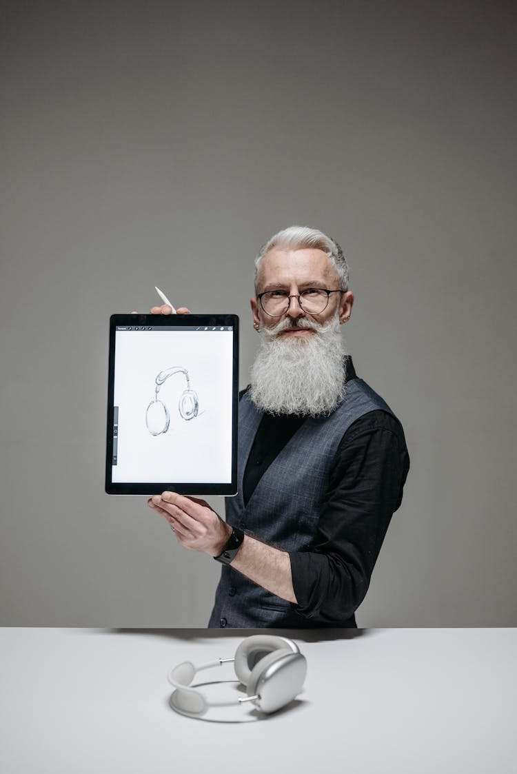 Man In Black Suit Holding A Tablet With Headphone Image On Screen 